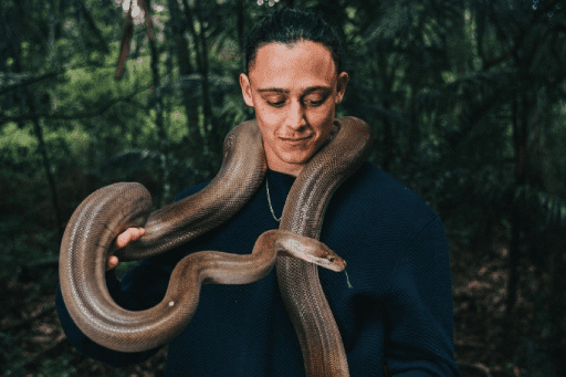 A man named Isiah holding a python snake who is a deadly keeper